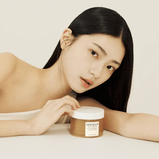 A woman holding SKIN1004 Centella Calming Pads for hydrating and soothing sensitive skin.